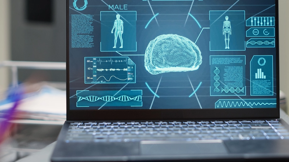 Open laptop displaying detailed medical holographic images including human anatomy, DNA strands, and brain scans, representing advanced medical technology and diagnostics.
