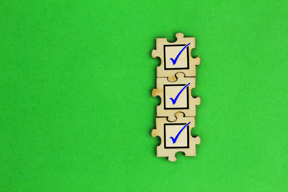 Four interlocked puzzle pieces with blue check marks on a vibrant green background, symbolizing task completion, achievement, or problem-solving.
