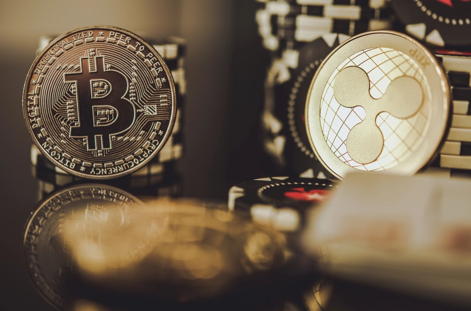 Close-up view of a Bitcoin and Ripple XRP coins against a blurred background of various cryptocurrency tokens, representing digital currency investment.