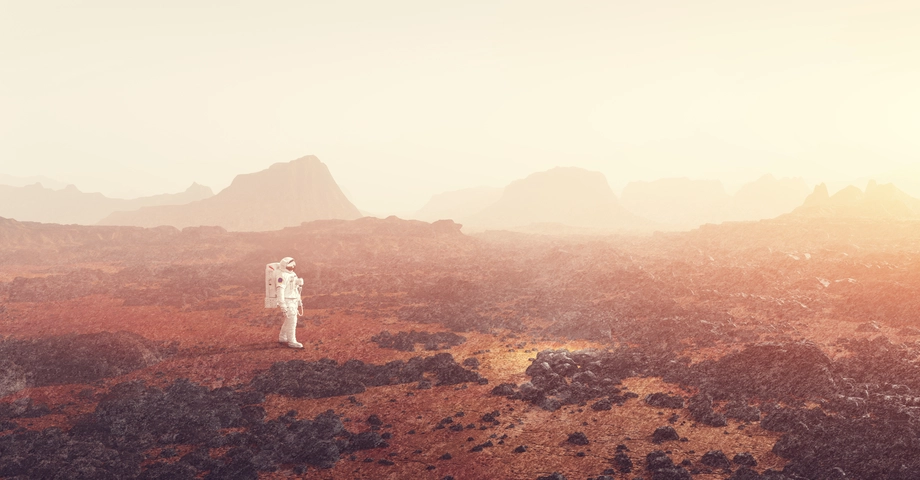 Astronaut exploring a vast, rocky Mars-like terrain under a hazy sky, illustrating space exploration and extraterrestrial landscapes.