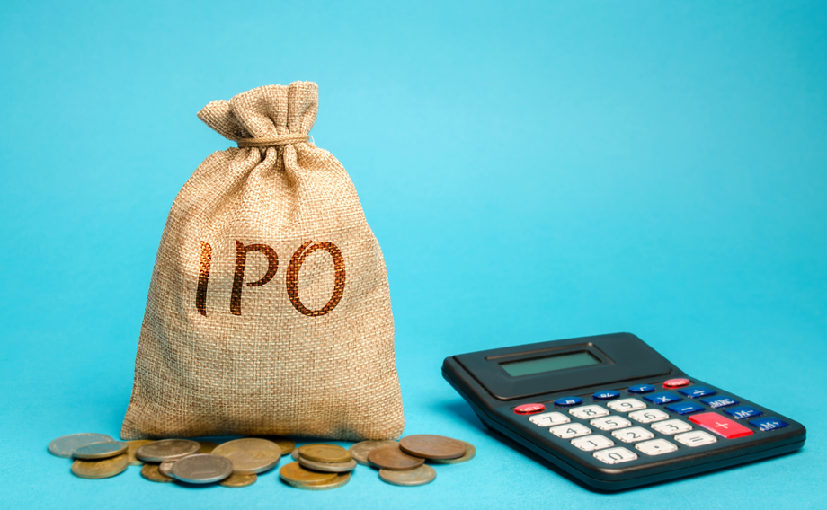 Burlap sack with 'IPO' printed on it beside a calculator and scattered coins on a blue background, representing initial public offering investment calculations.