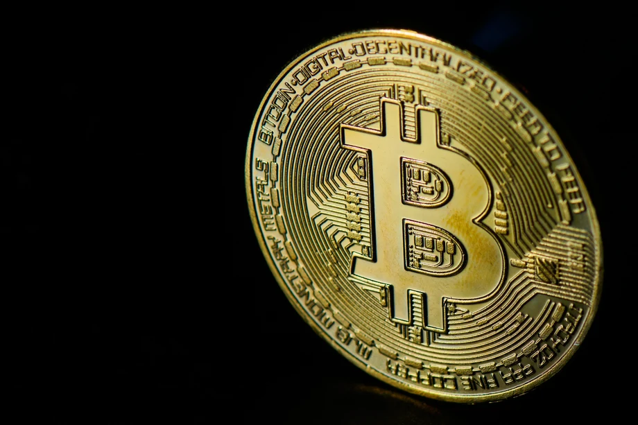 Close-up of a golden Bitcoin coin on a dark background highlighting its intricate design.