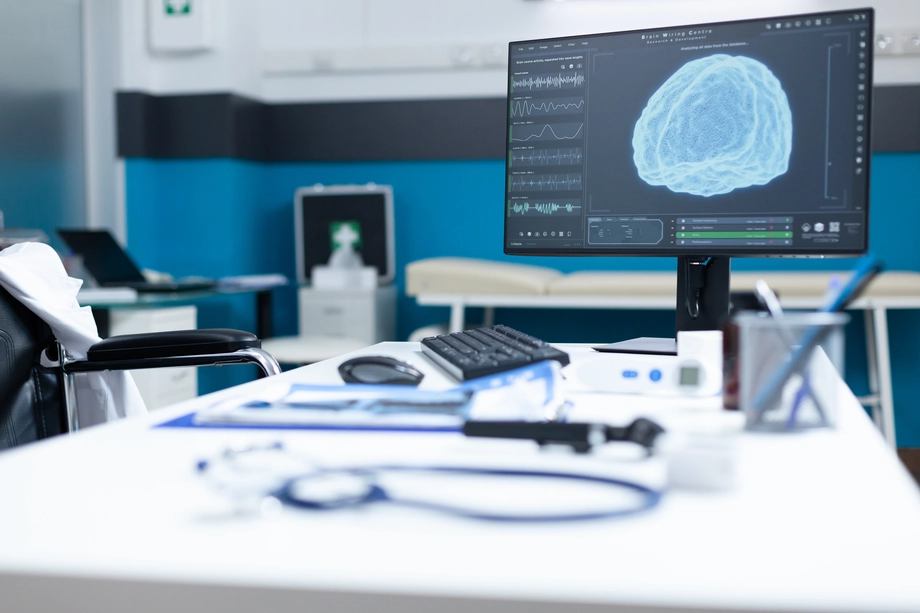 Modern neurology research office with an advanced brain scan displayed on a monitor, medical equipment, and empty wheelchair in focus