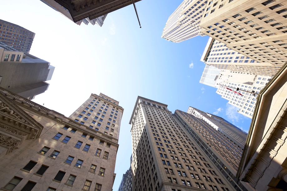 Worm's-eye view of skyscrapers against a clear blue sky in a bustling city's financial district